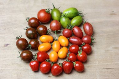 Tahta bir masanın üzerinde çeşitli taze domatesler var.