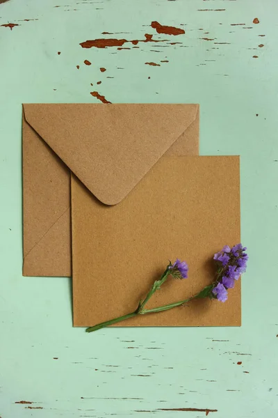 ペンキが剥がれたミントの背景の上に紫色の花が咲く空の茶色のカード — ストック写真
