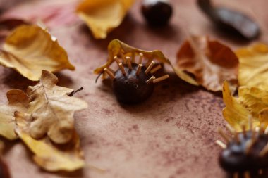 Renkli sonbahar yaprakları ve kahverengi suluboya arka planda at kestanesinden yapılmış hayvanlarla dolu bir hayat.