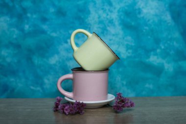 Renkli seramik kaseler, kahve fincanları ve çaydanlık mavi arka planda bir masada. Metin için boşluk