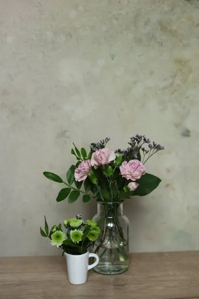 Bouquet of carnations and chrysanthemum flowers in a vase on a wooden table