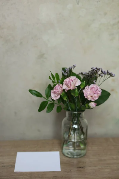 bouquet of pink carnations in a vase on a wooden table. copy space.