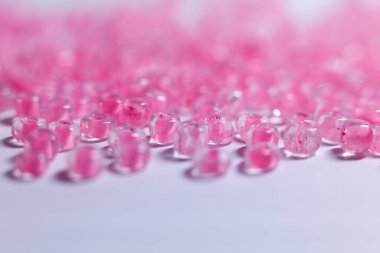 Bir sürü küçük pembe boncuklu beyaz bir arka plan.