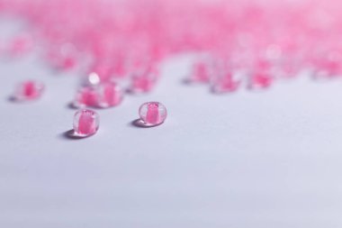 Bir sürü küçük pembe boncuklu beyaz bir arka plan.