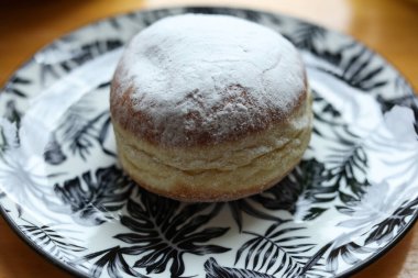 Tahta bir masada, tabakta krema şekerli çörek..