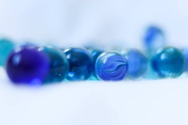 Beyaz arka planda mavi cam misketler. Yakın plan, makro fotoğraf.