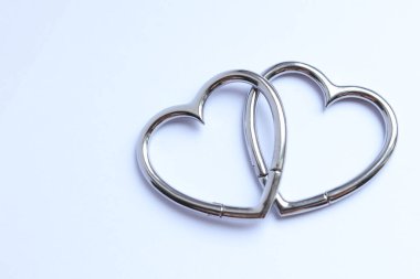 Beyaz arka planda kalp şeklinde paslanmaz çelik küpeler.