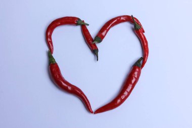 Beyaz arka planda kalp şeklinde kırmızı kırmızı kırmızı biber.
