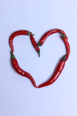Beyaz arka planda kalp şeklinde kırmızı kırmızı kırmızı biber.