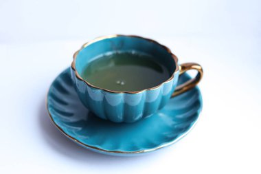 Beyaz arka planda fincan tabağı olan mavi çay..