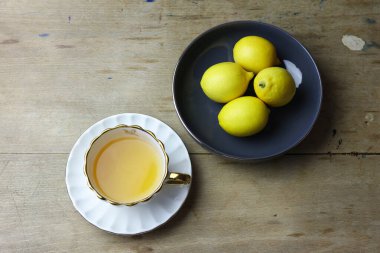 Limonlar ve bir fincan çay ahşap masada, hayat devam ediyor.