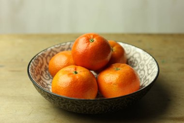 Olgun mandalinalarla dolu bir hayat Tahta bir masada bir kasede.