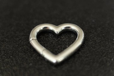 Siyah arka planda gümüş kalp şeklinde küpe. Makro fotoğraf.