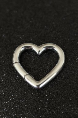 Siyah arka planda gümüş kalp şeklinde küpe. Makro fotoğraf.