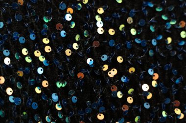 Arka plan olarak siyah kumaş üzerindeki renkli pullar. makro