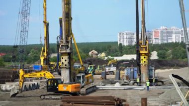 Büyük sondaj makinesi Irpin 'de bir köprü yapımında sütunları kaldırmak için delikler açıyor. Ukrayna. İnşaatçılar ve inşaat ekipmanları köprünün sütunlarını kurmaya çalışıyorlar. Yüksek