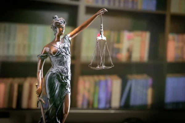Goddess of justice statue in lawyer cabinet on bookshelf background