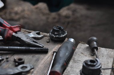 Tahta bir bankta aletlerle birlikte duran eski bir bisiklet. Parçaların değiştirilmesi, tatil başlamadan önce en sevdiğiniz bisikletin bakımı