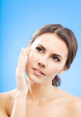 Cilt dokunmak veya krem, mavi arka plan üzerinde uygulama güzel bir genç kadın portresi