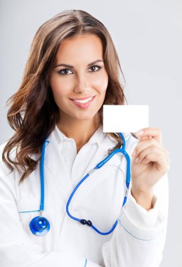 mutlu gülümseyen genç kadın doktor boş kartvizit veya davetiye, gri arka plan üzerinde gösterilen portresi