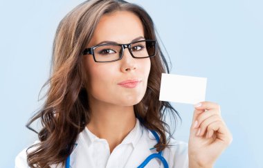 mutlu gülümseyen genç kadın doktor boş kartvizit veya davetiye, mavi arka plan üzerinde gösterilen portresi