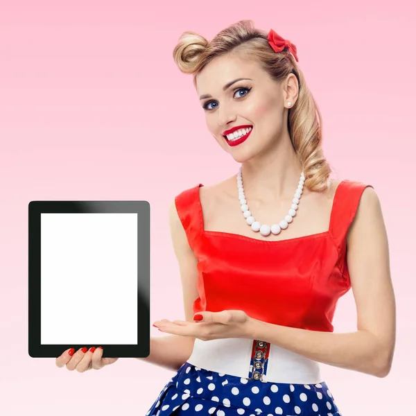 展示空白的无名氏平板电脑显示器 与彩色空间 穿着别针风格的衣服在波尔卡圆点 粉红背景 复古时尚拍摄中的白种人金发模特 — 图库照片