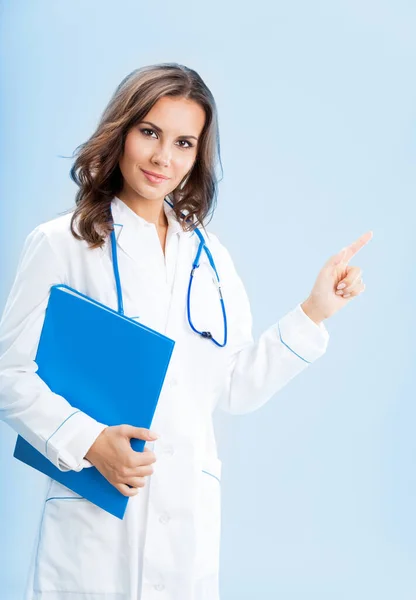 何かを示す若い女性医師の肖像または製品または記号文字 青い背景上の青い Foder に対して Copyspase — ストック写真