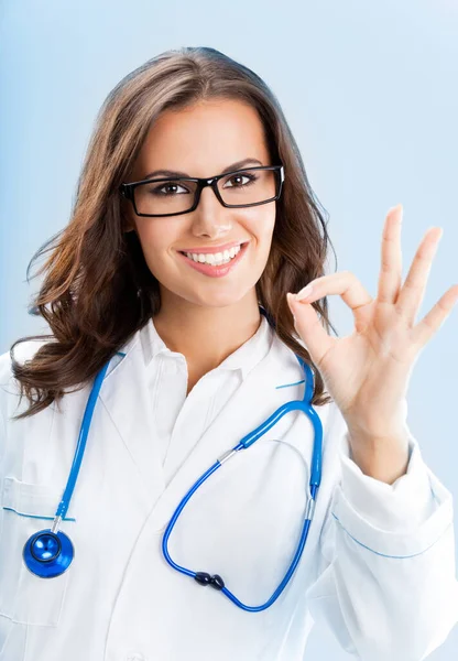 在蓝色背景显示好的姿态 快乐微笑着年轻女医生 — 图库照片