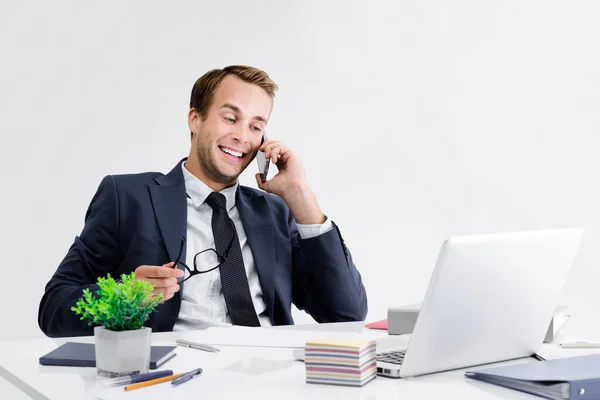 Młody Uśmiechnięty Biznesmen Czarny Garnitur Pracujący Telefonem Komórkowym Laptopem Biurze — Zdjęcie stockowe