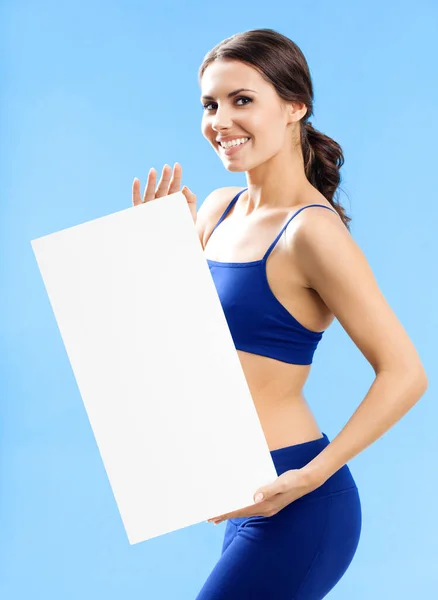 性格开朗的年轻女子在健身中穿上蓝色背景显示空白招牌或 Copyspace — 图库照片