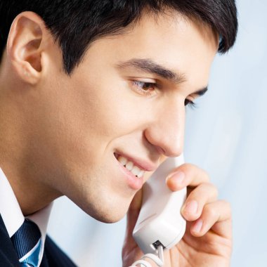 genç gülümseyen iş adamı veya çağrı merkezi çalışan ofis telefon ile portresi