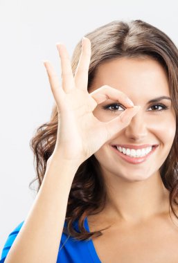 iyi bir jest, gri arka plan üzerinde gösterilen neşeli genç gülümseyen kadın portresi