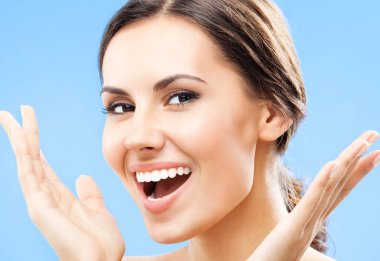 Mavi arka planda gülümseyen güzel genç bir kadının portresi.