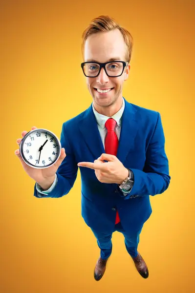 形象滑稽的快乐商人的眼镜显示时钟 蓝色西服和红色领带 顶部角度拍摄 橙色背景 业务和时间概念 免版税图库图片
