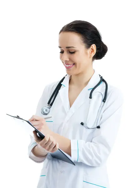 快乐微笑女性年轻的医生在剪贴板中 孤立在白色背景上写 图库照片
