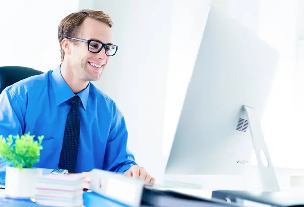 快乐微笑的年轻商人 穿着自信的衣服 蓝色衬衫 领带和眼镜 与办公室的台式电脑一起工作 工作和教育概念方面的成功 — 图库照片