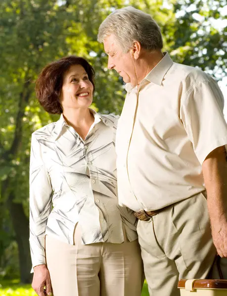 Senior happy smiling couple walking in park, looking at each other, outdoor shot