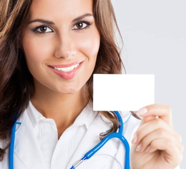 Gri arkaplan üzerinde boş kartvizit ya da davetiye gösteren kadın doktor portresi