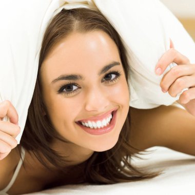 Yatakta uyanan güzel, gülümseyen kadın. 