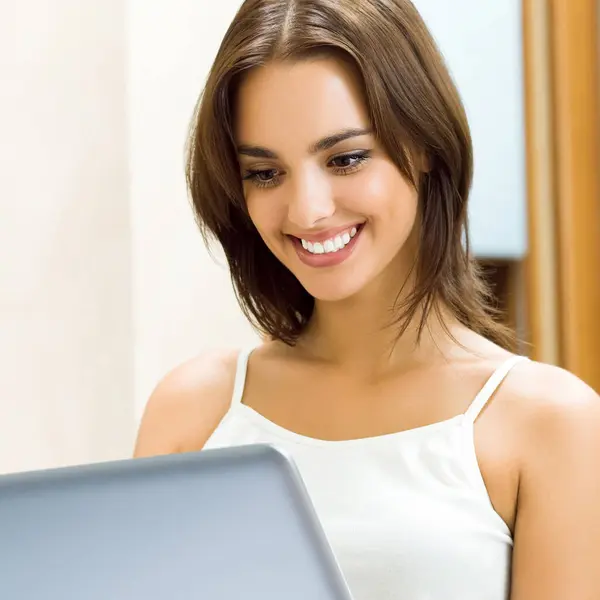 在家里用笔记本电脑工作的漂亮女人笑着 — 图库照片
