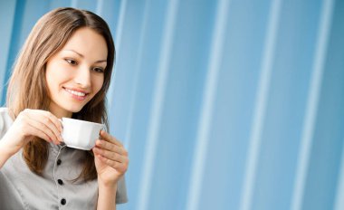 Neşeli gülümseyen iş kadını ofiste fotokopi odasıyla kahve içiyor.