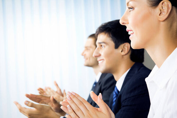 Счастливые бизнесмены аплодируют в офисе
