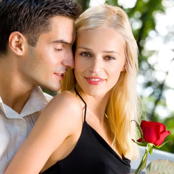 年轻快乐多情开朗夫妇与室外的玫瑰 图库图片