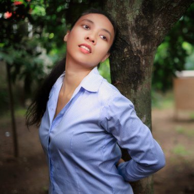 Endonezyalı kız ağacın yanında poz veriyor.