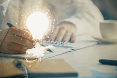 El üstünde tutulan ampul hologramı notlar alıyor. Fikir kavramı. Çift pozlama