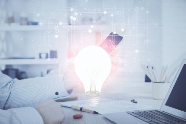 Dijital bir cihaz ve ampul hologram çizimi kullanarak insanın ellerini tutarken çift pozlama. Fikir kavramı.