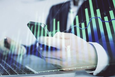 Dijital telefon ve forx grafik çizimi kullanarak adamın elini tutarken birden fazla pozlama. Finansal piyasa kavramı.