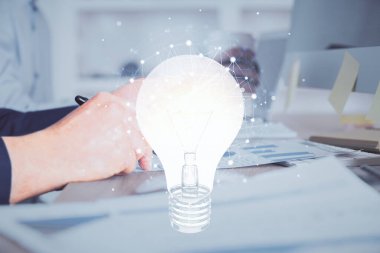 Dijital bir cihaz ve ampul hologram çizimi kullanarak insanın ellerini tutarken çift pozlama. Fikir kavramı.