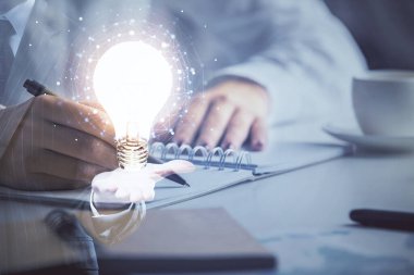 El üstünde tutulan ampul hologramı notlar alıyor. Fikir kavramı. Çift pozlama