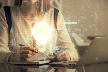 Bilgisayarda yazı yazan ve ampul çizen bir kadının ellerine iki kez maruz kalmış. Fikir kavramı.